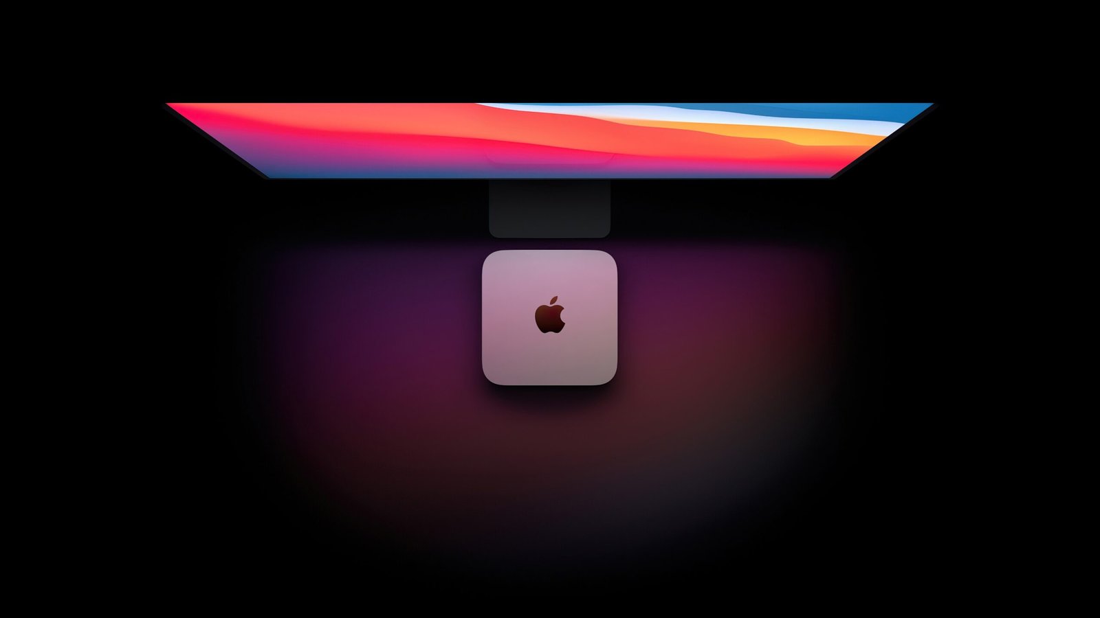 Sleek computer monitor on a rounded stand against a dark background, screen showing a vibrant gradient of reds, pinks, and blues.