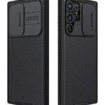 Black carbon‑fiber textured smartphone case with a built‑in kickstand on the back, shown around a multi‑lens camera setup on the phone/side view. Improvements: None needed.