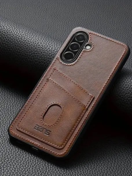 Back of a brown leather wallet-style phone case with a card slot beside a triple-camera phone on a dark textured surface.