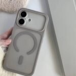 Gray phone case with a circular ring grip on the back, held by a hand near a laptop lid/edge.