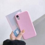 img_8358 - The Phonepreneur Global Person holding a pink smartphone case with a translucent card against a light wall.